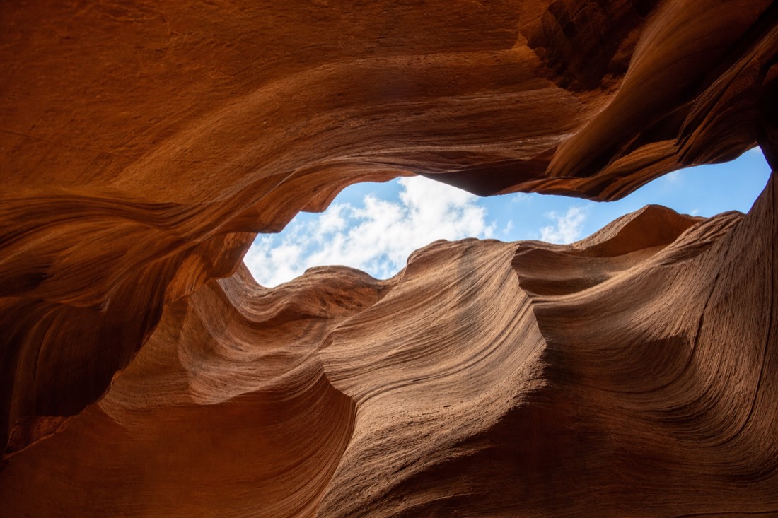 Narrow slot canyon ceiling opening with winter sky visible and no light beam