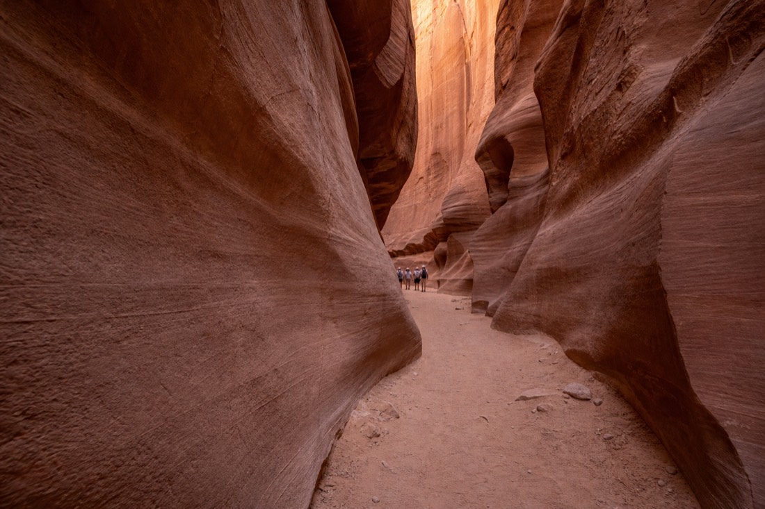 Nearly empty slot canyon corridor with a single small tour group in the distance