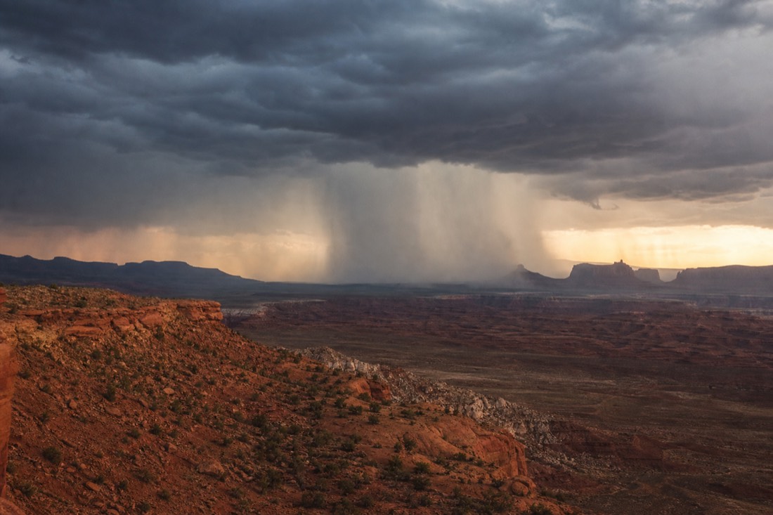 Dark monsoon storm cell dropping a column of rain on distant mesas in the Arizona desert