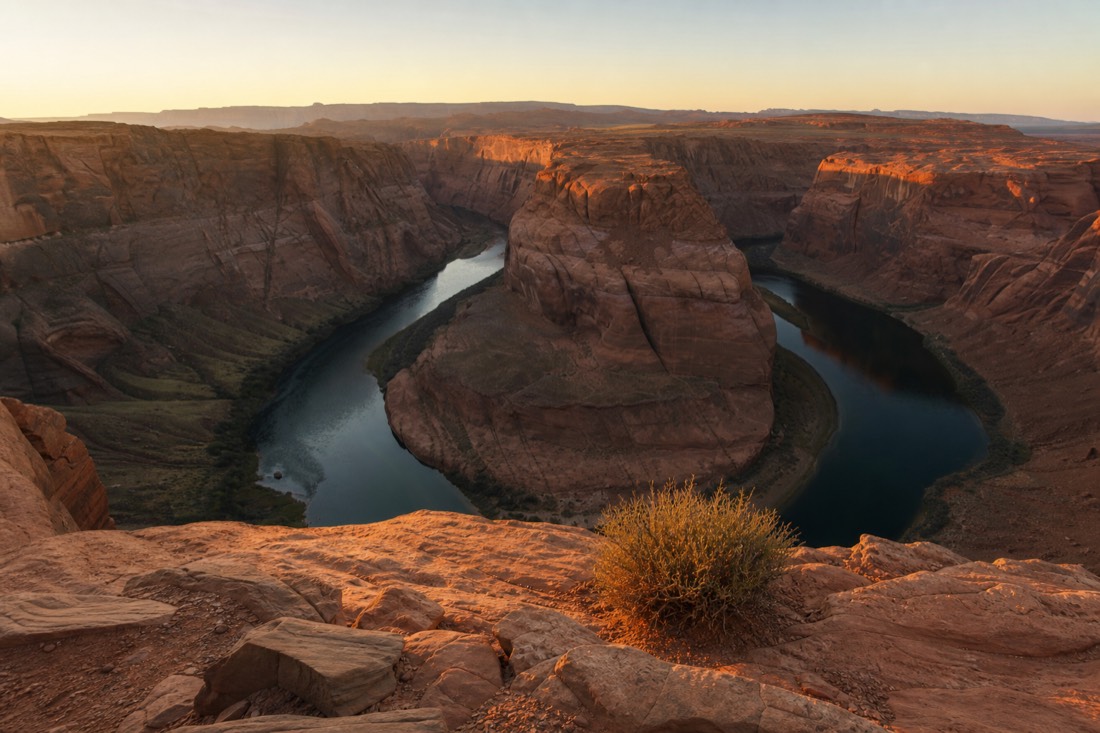Sunrise light hitting a horseshoe shaped river bend viewed from a sandstone rim