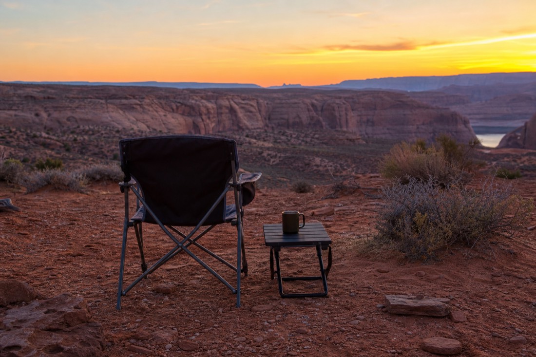 Camp chair and mug facing distant sandstone cliffs at dusk near Page Arizona
