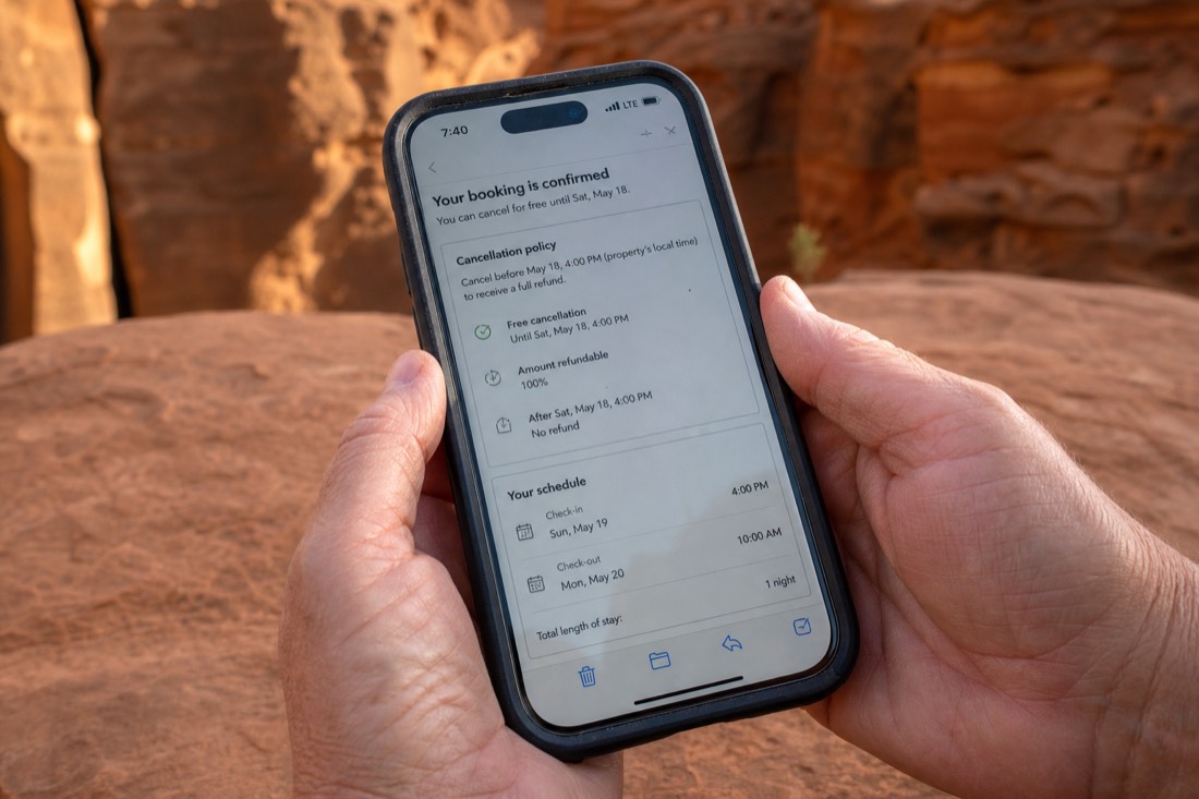 Close-up of hands holding a phone displaying a booking confirmation with cancellation details