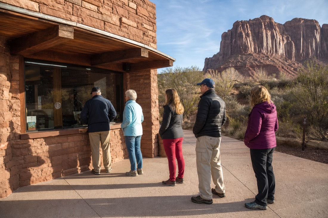 Park entrance fee window with a small queue of visitors in desert morning light