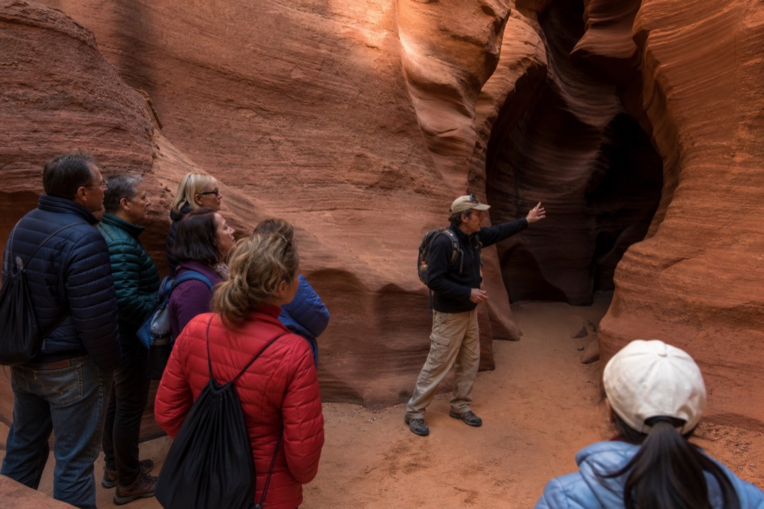 Visitors listening to a guide at golden hour outside a slot canyon entrance