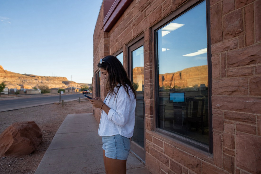 Traveler checking a booking confirmation on a phone outside a tour office in Page