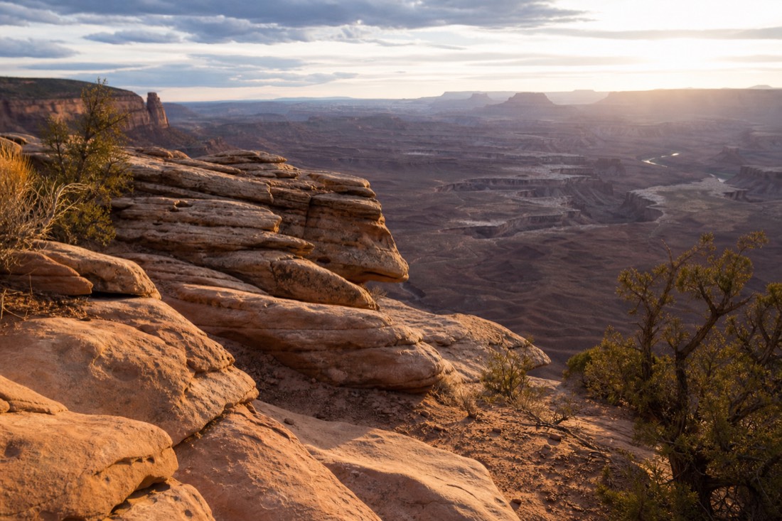 Traveler at a canyon rim viewpoint in late afternoon light with layered gorge below