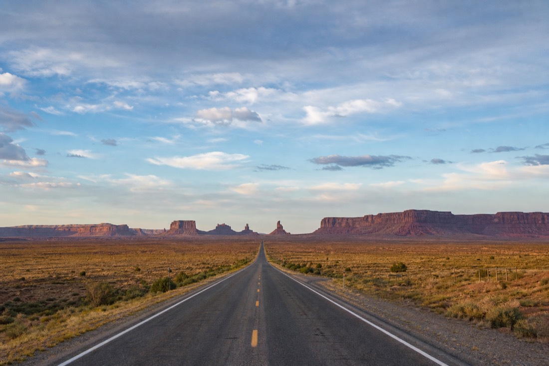 Long straight desert highway stretching to the horizon under a huge sky