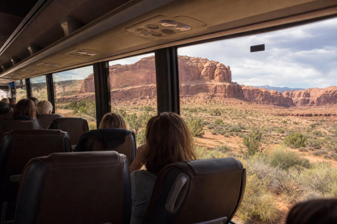 Comfortable coach interior with passengers watching desert scenery through large windows