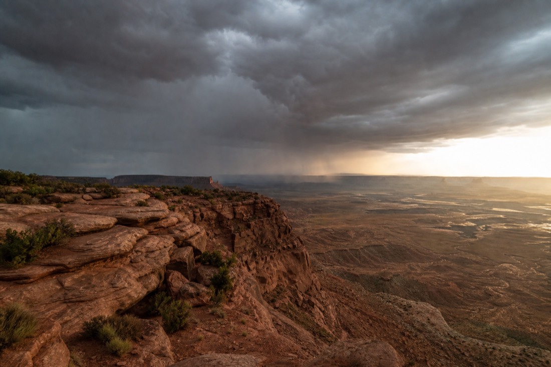 Dramatic monsoon clouds over desert cliffs with sunlight breaking through