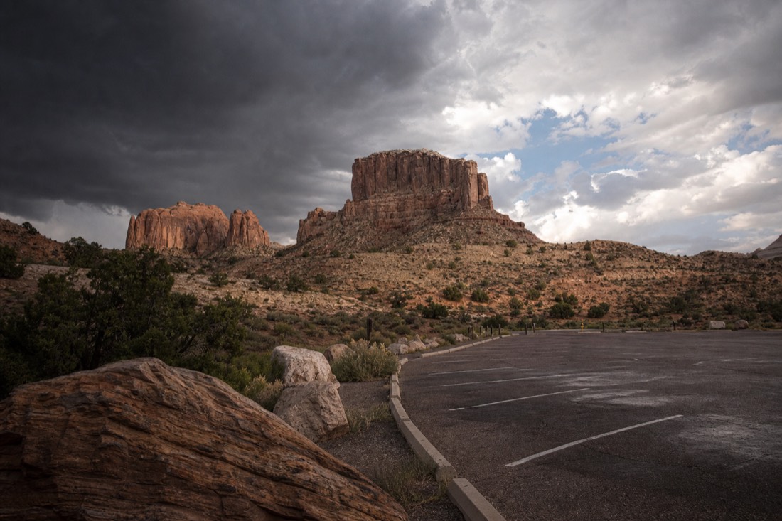 Storm clouds gathering over desert mesas beside an empty tour parking lot