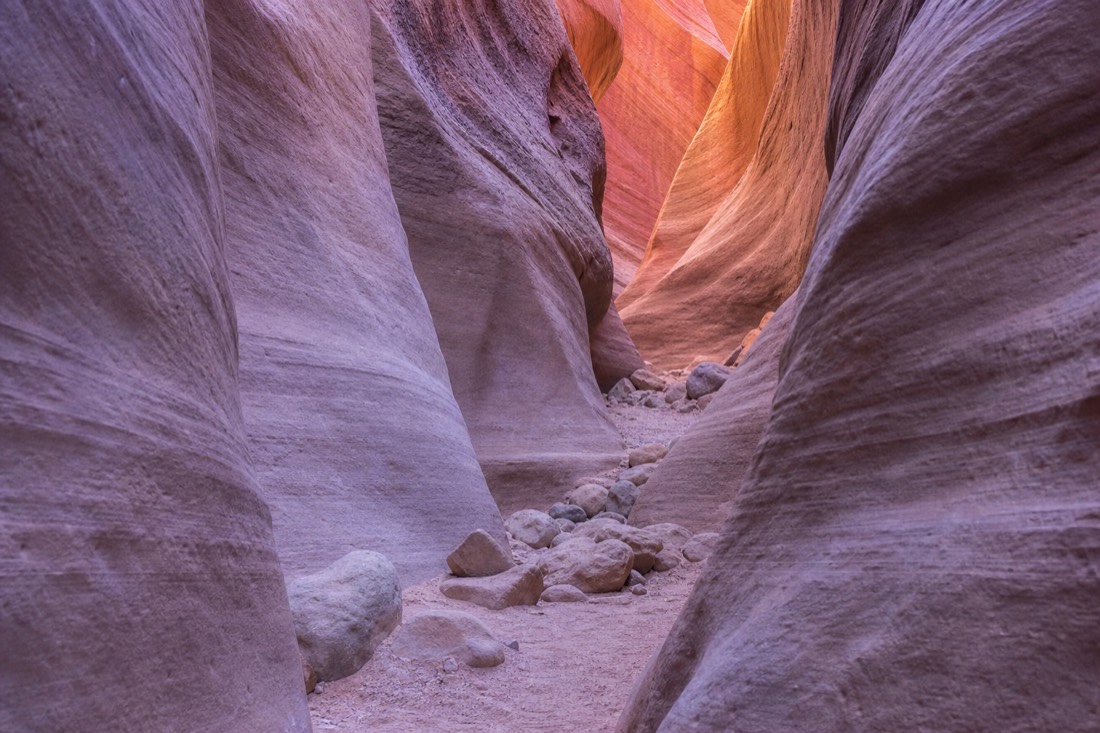 Soft winter light inside a quiet slot canyon with pastel purple and orange rock tones