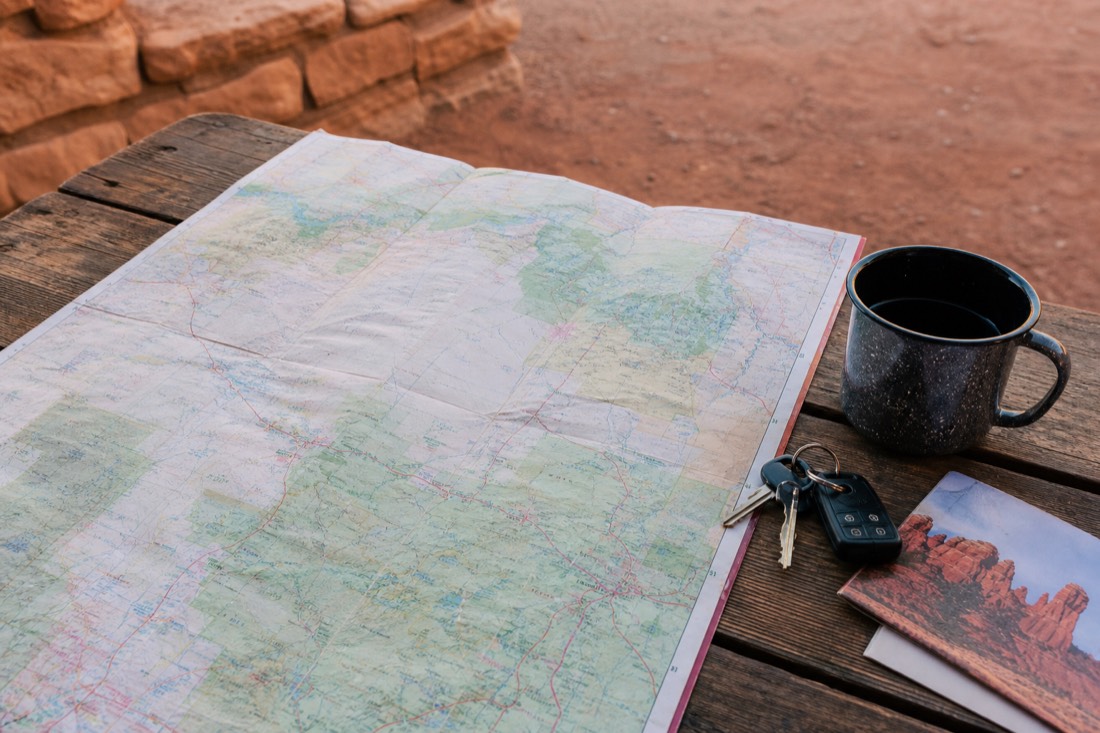 Road trip planning scene with a paper map of northern Arizona, coffee and car keys on a wooden table