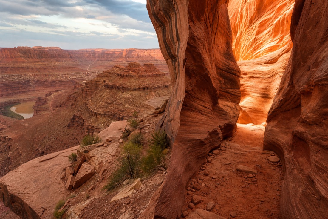 Split scene of a wide canyon rim vista beside a narrow glowing slot canyon passage
