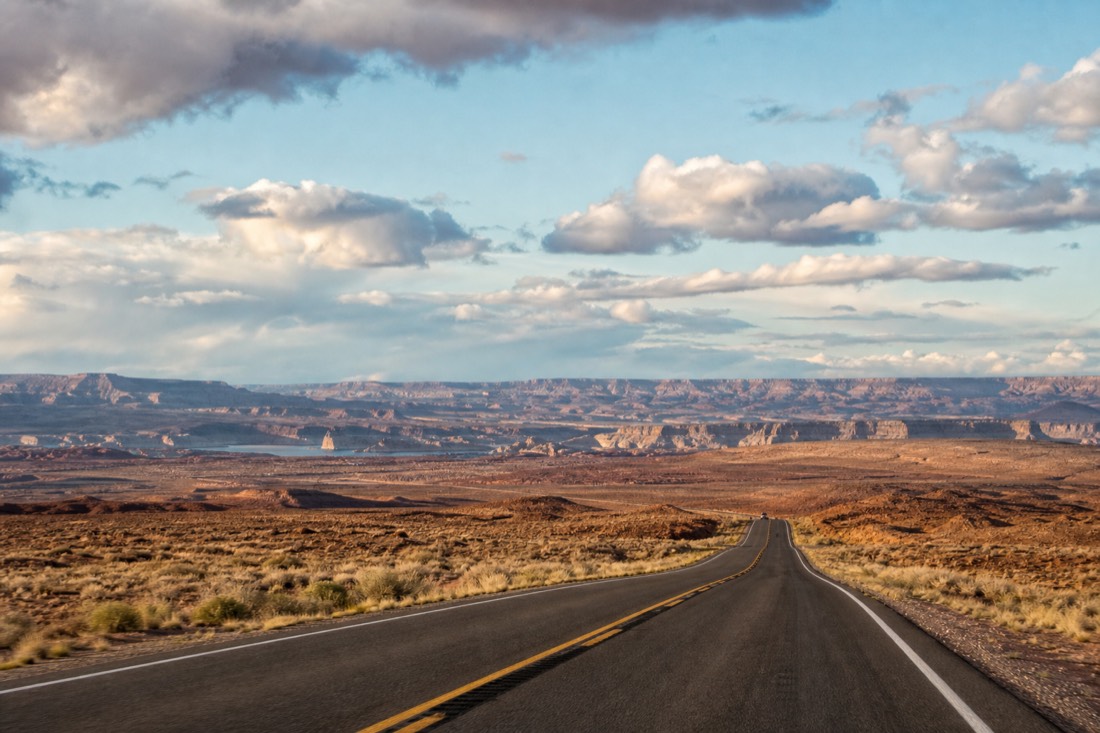 Desert highway approaching Page Arizona with canyon country and afternoon clouds on the horizon