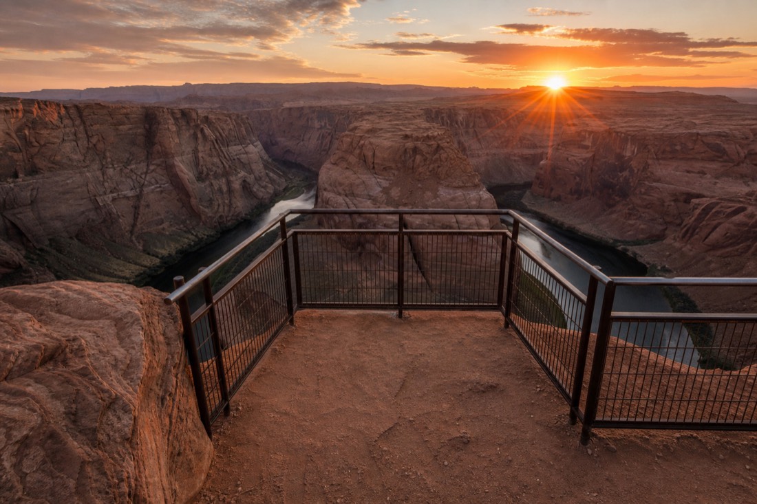 Railed viewing platform at the Horseshoe Bend overlook with open unfenced sandstone rim stretching away on either side