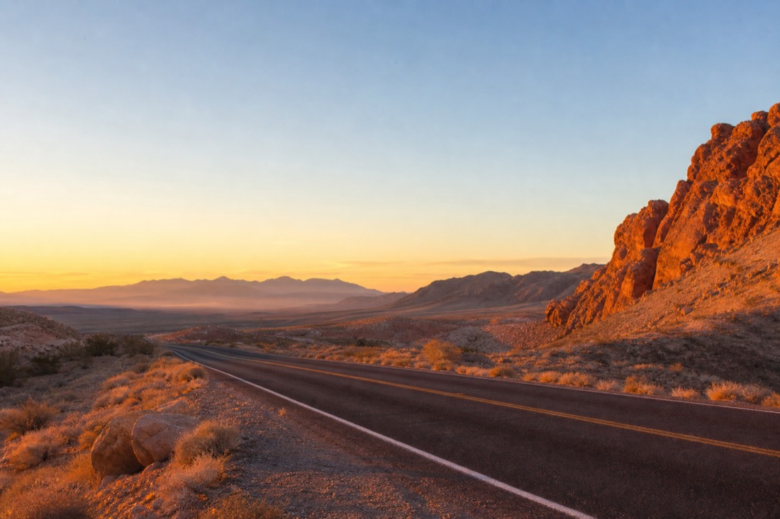 Sunrise light over a desert highway as an early morning tour departs Las Vegas