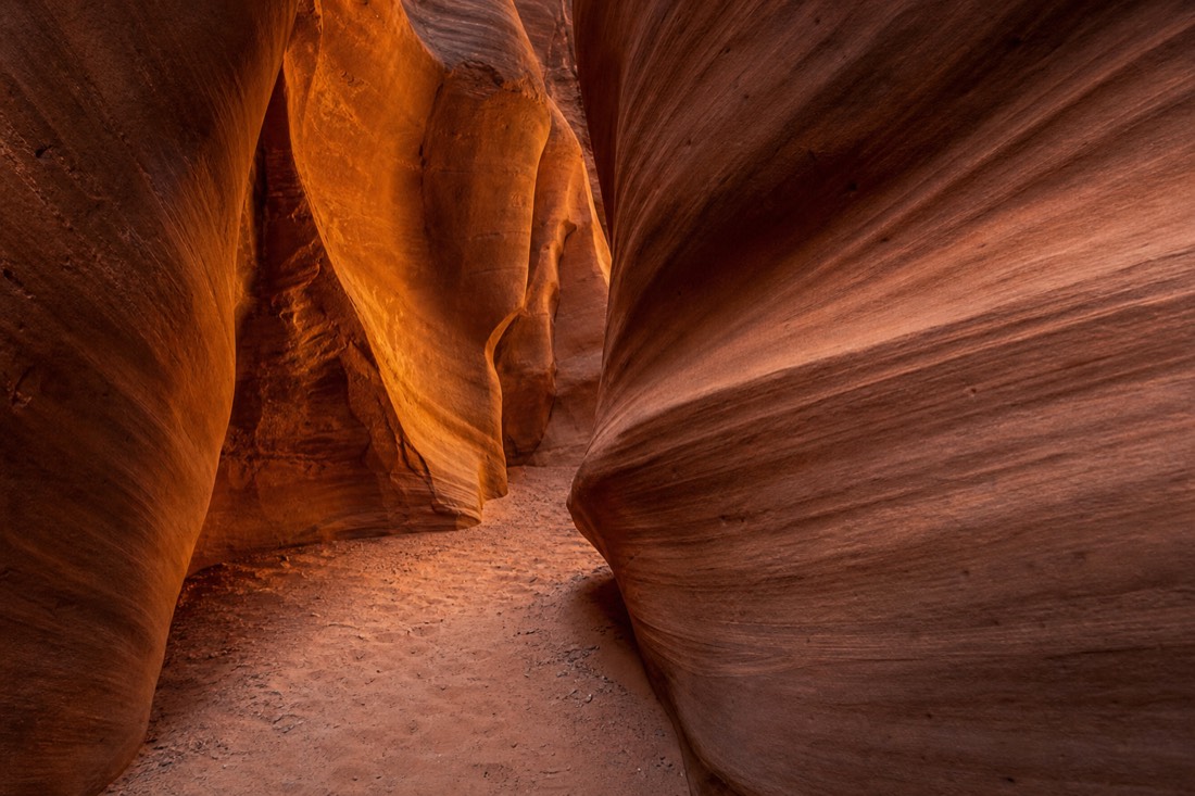 Warm light glowing on curved sandstone walls inside a narrow slot canyon