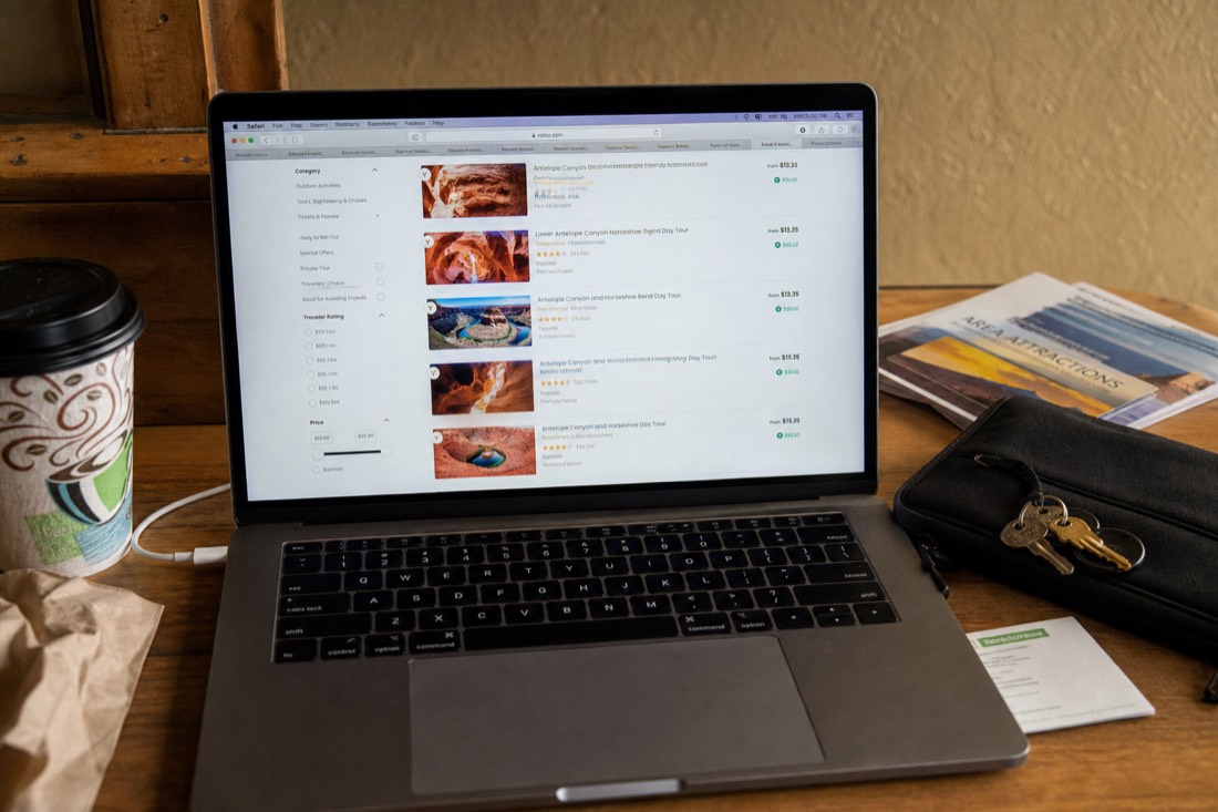 Traveler comparing several similarly named canyon tour listings on a laptop at a Page hotel desk