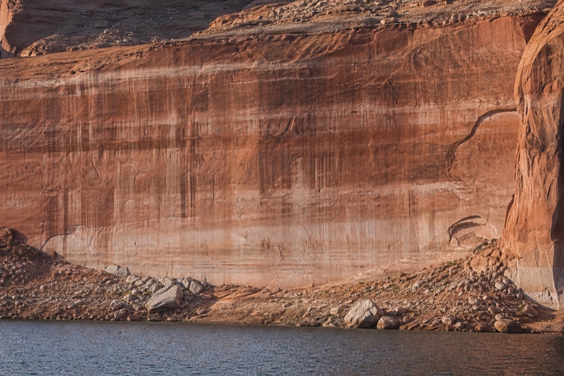Lake Powell shoreline showing a pale bathtub ring high on the red cliffs above the current water line