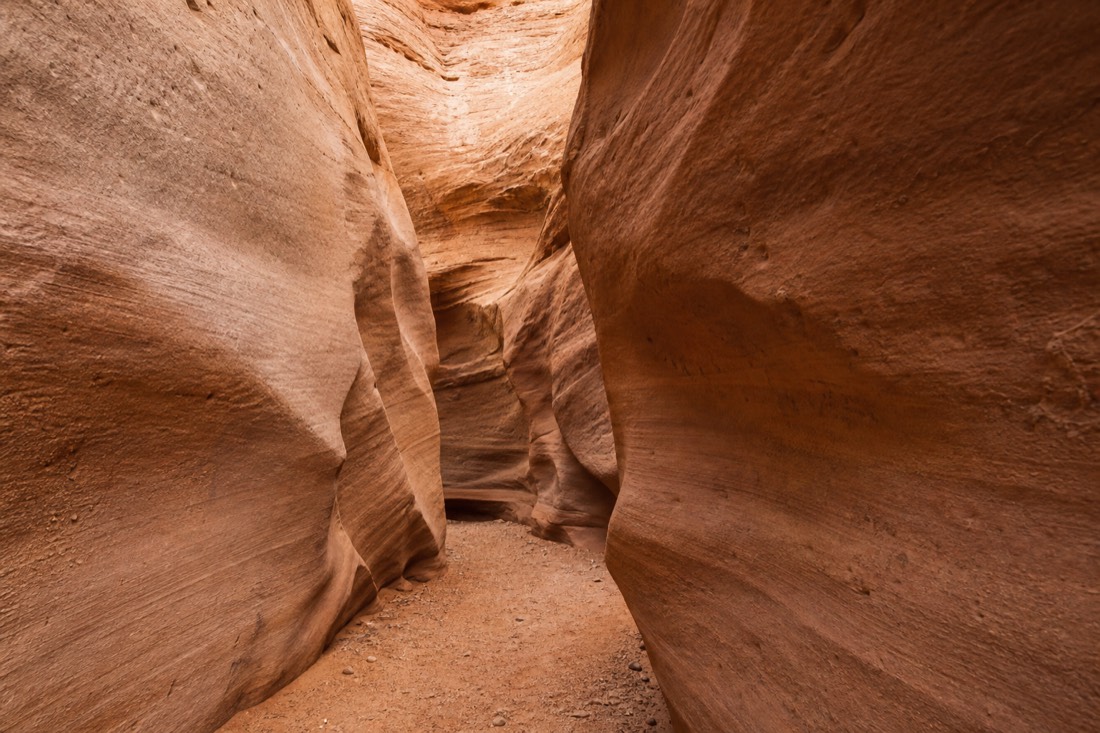Narrow sandstone slot canyon walls carved smooth by the force of past flood water